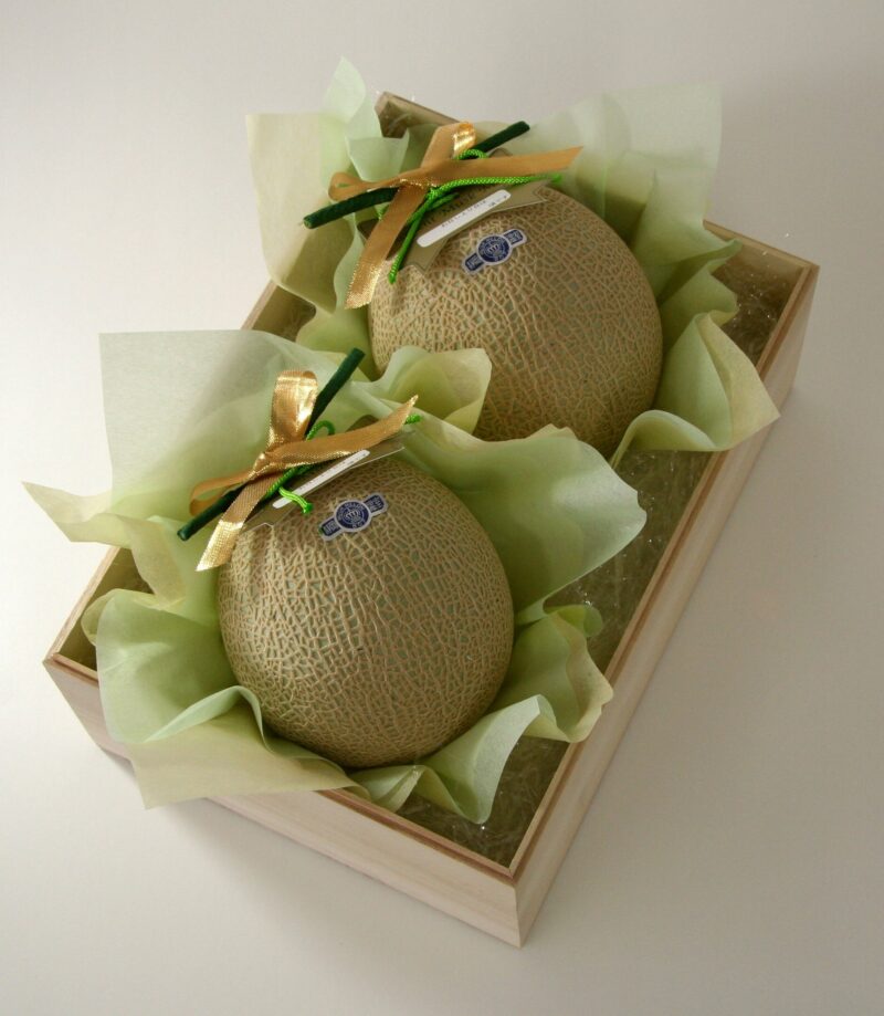 Japanese Omiyage 3 Two large melons in a wooden box placed on green paper as they are presented as Japanese omiyage