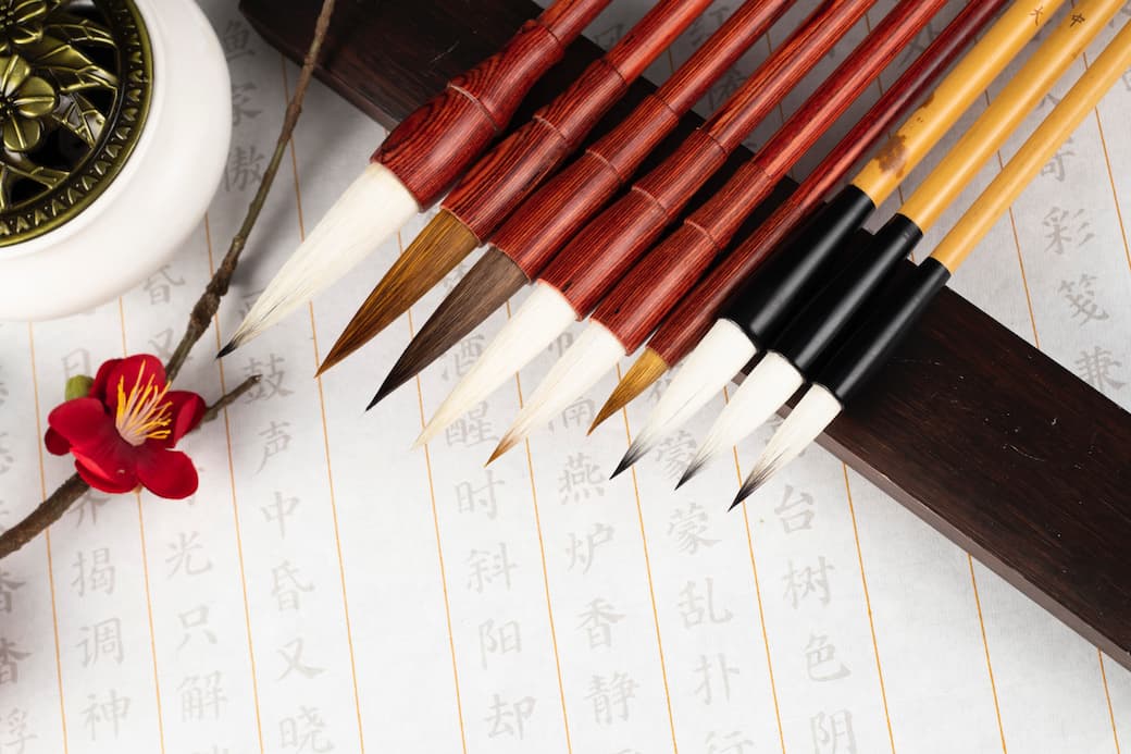 Things to do in Nara 1 Nine brushes laid out over some paper with Japanese calligraphy with small flower in the corner