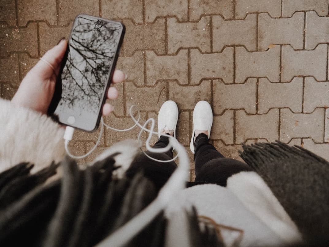 Podcasts in Japan 4 A girl looks down and looks at her cellphone with earbuds attached as she listens to a podcast in Japan