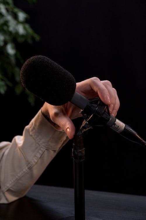 Podcasts in Japan 1 A hand grasping a microphone in a dark room preparing to record a podcast in japan