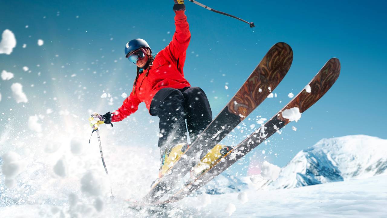 Sports in Japan 4 A person skiing while kicking up a lot of snow as they make a small jump