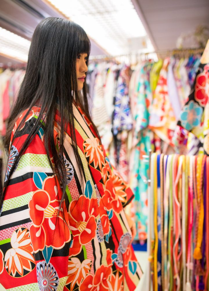 Kimono Rental 1 Japanese woman trying on a red kimono with an intricate design in a kimono rental store