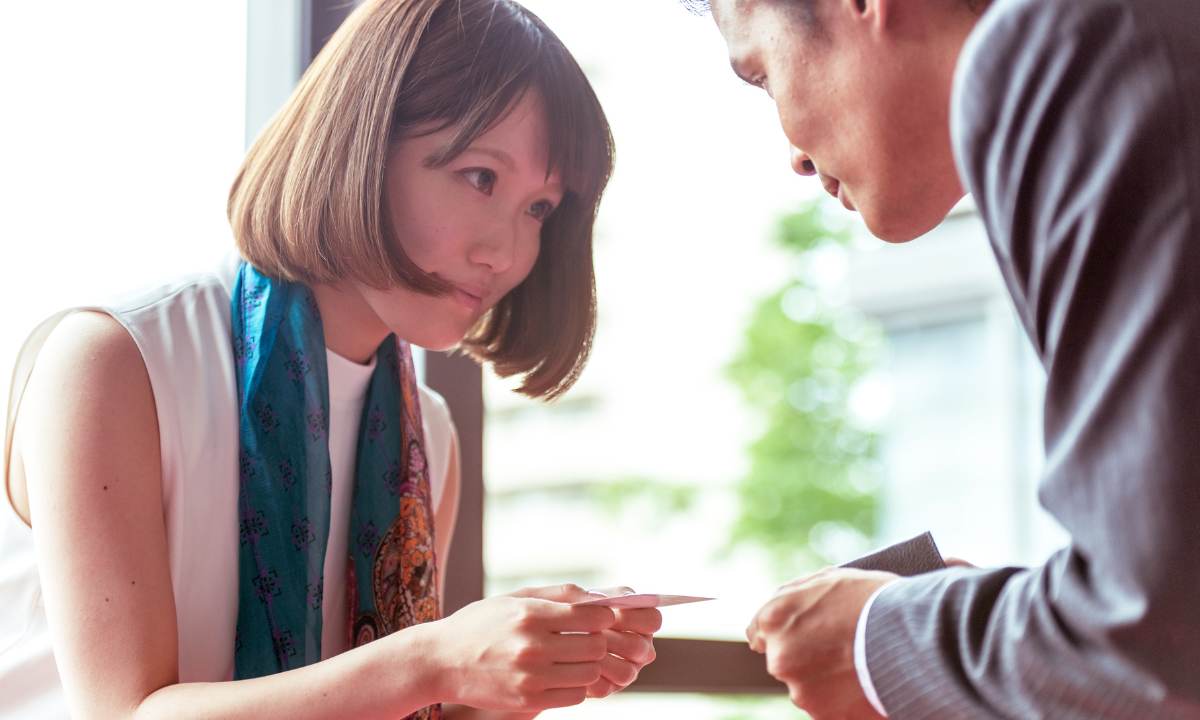 Woman exchanging buisnesscards with man wearing a suit