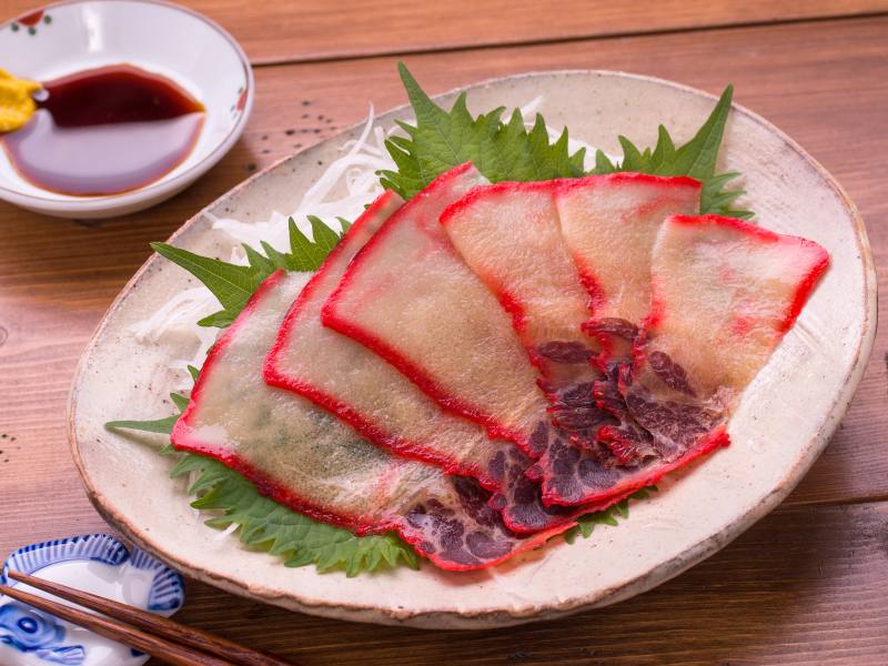Kujira kujira on a plate (white meat in the center, bright pink on the edges, a weird japanese food based on looks but tastes like meat)