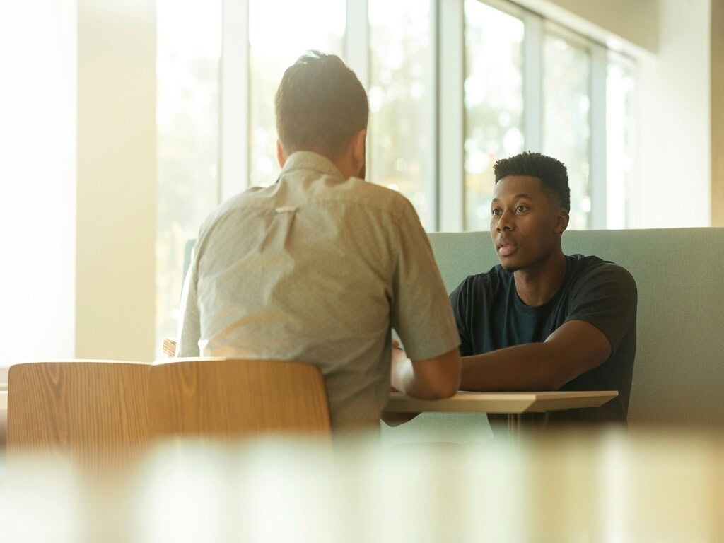 The two men discussing the Japanese proverbs while sitting by the table, facing to each other.