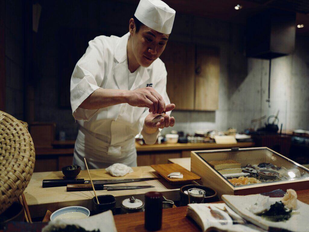 At an authentic sushi restaurant, chef is making a sushi at the counter.