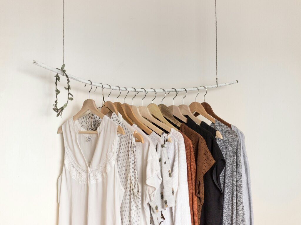 With the white background, various colors of clothing are hanging on a clothing rack.