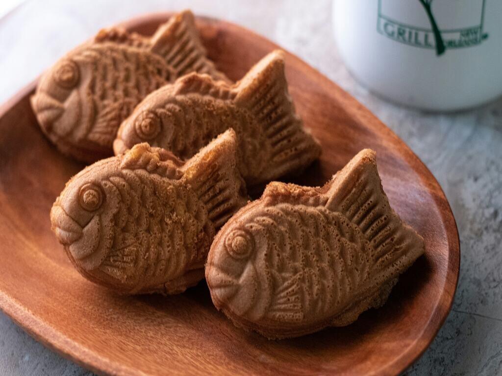 On a wooden plate, 4 pieces of taiyaki are placed neatly.