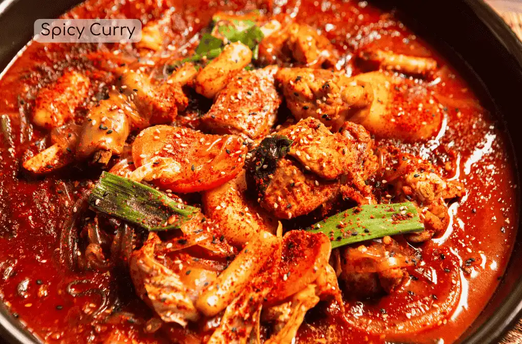 An image of a spicy curry in a black bowl with toppings such as chicken and spices