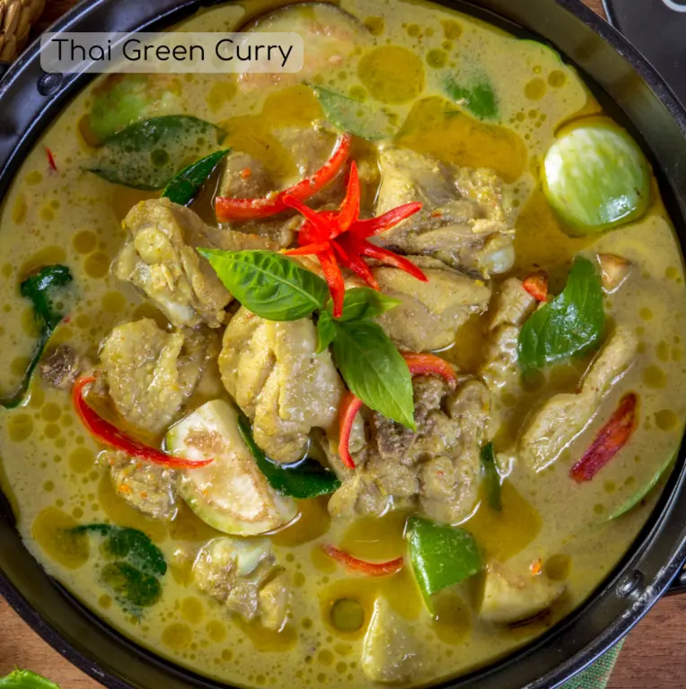 An image of a Green Thai Curry in a bow with toppings such as chicken, red bell pepper, green bell pepper, onions, and chilli