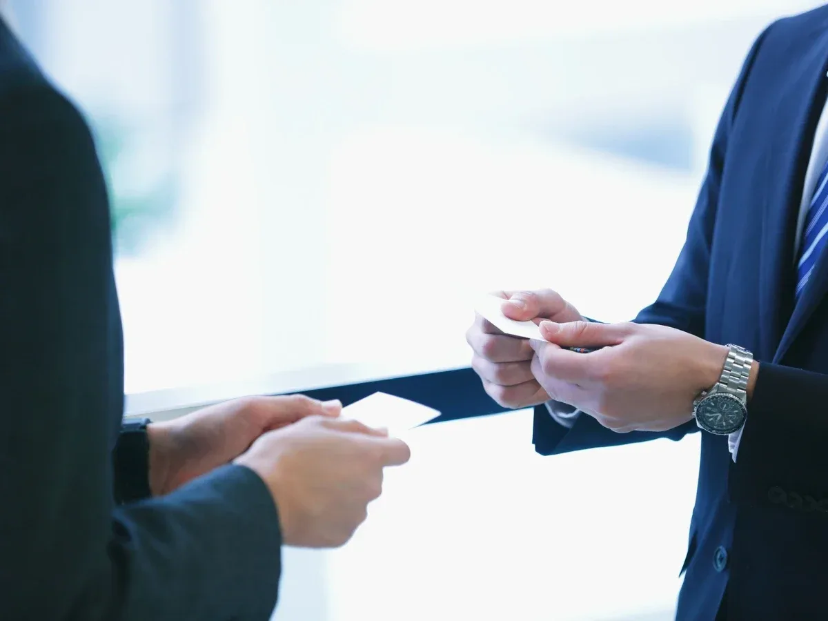 two individuals holding japanese business card, preparing for exchange